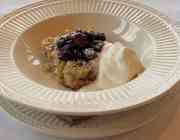A bowl on charger filled with baked lemon and strawberry compote.